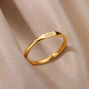 Close-up of golden stainless steel ring featuring 222 angel number engraving on silk
