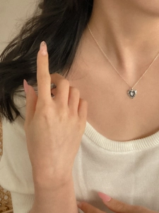 Close-up of a 925 sterling silver heart necklace with star detail on a female model