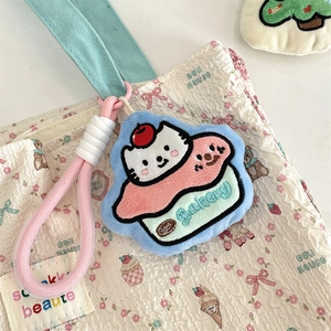 Macro shot of embroidered cat cupcake plush charm with pink lanyard on floral bag