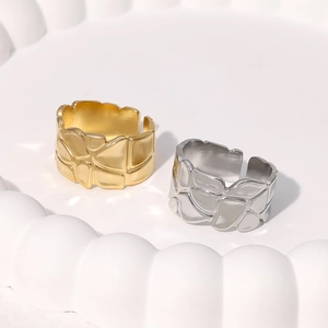 Dettaglio di ampi anelli aperti con texture geometrica irregolare in oro e argento