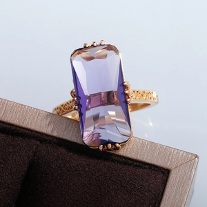 Macro detail of luxury vintage gold ring with large emerald-cut purple zircon