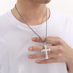 Detail of silver double-layered cross pendant with twisted rope chain on white tee