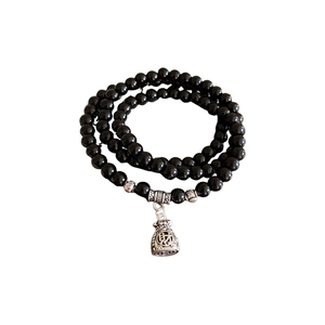 Three-layer black obsidian beaded bracelet with silver fortune bag charm on white background