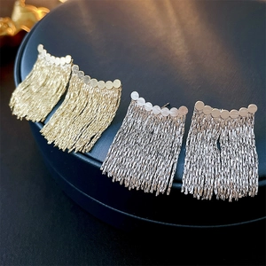 Elegant gold and silver metallic tassel earrings with geometric studs on blue jewelry box