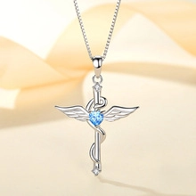 Macro detail of S925 silver necklace with cross, angel wings, and blue heart gemstone