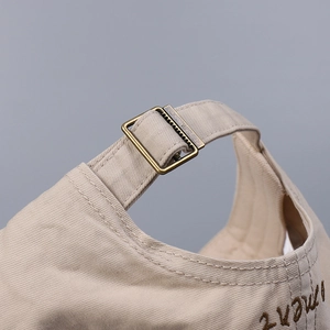 Macro shot of khaki cotton baseball cap with adjustable bronze buckle and fine stitching