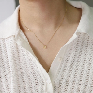 Detail of single round zirconia pendant on gold plated stainless steel chain necklace