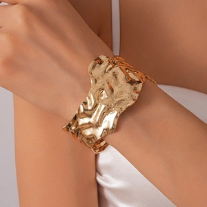 Détail du large bracelet manchette doré avec texture irrégulière et design moderne lava