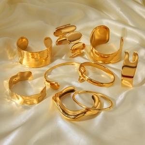 Macro shot of assorted gold stainless steel bangles on champagne silk fabric background