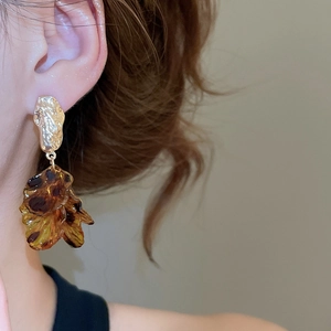 Detail view of retro amber acrylic petal earrings with golden textured metal drop