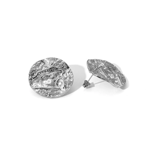 Macro view of silver round stud earrings featuring unique hammered texture and metal gloss