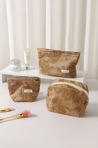 Detailed view of floral embroidery and metallic zippers on linen cosmetic bags
