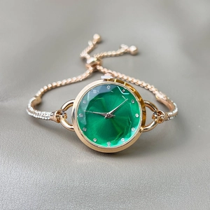 Detailed view of women's gold watch with green dial and sparkling rhinestone strap