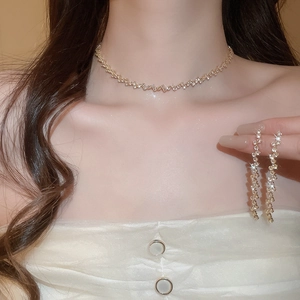 Close-up of elegant gold tassel earrings and matching zircon necklace on a model
