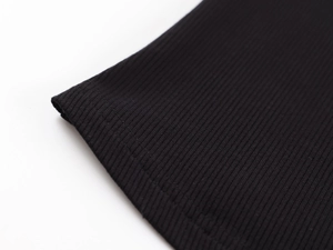 Detailed close-up of black ribbed knit fabric hem and fine stitching on a V-neck tank top