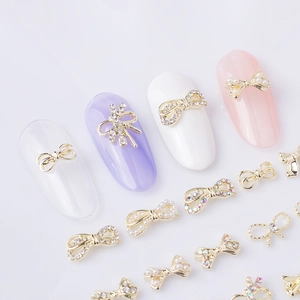 Detail view of 3D alloy bow nail art charms with pearls and rhinestones on gold base