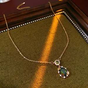 Gold plated necklace with green emerald pendant and butterfly accents on velvet