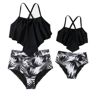 Matching family tankini set with black ruffle tops and tropical palm leaf print bottoms