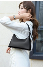 Close-up of minimalist black leather underarm bag featuring matte texture and shoulder strap