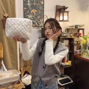 Détail d'une grande trousse de maquillage matelassée blanche tenue par une personne