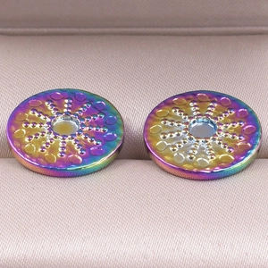 Macro shot of rainbow stainless steel round stud earrings with textured relief in a jewelry box