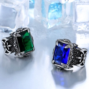 Close-up of men's punk rings with green and blue gemstones on ice-themed background