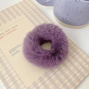Detail shot of fluffy purple plush hair tie showing soft texture on a checkered background