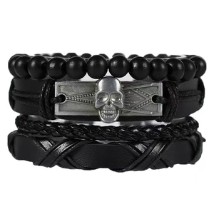 Détail d'un ensemble de bracelets en cuir noir avec perles et breloque tête de mort