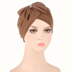 Detail of a brown turban hat showing a large bow with sparkling rhinestone accents
