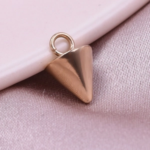 Macro shot of rose gold conical pendant accessory on soft pink satin fabric background