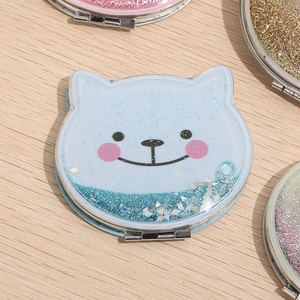 Close-up of blue cat-shaped glitter quicksand folding mirror on wooden surface