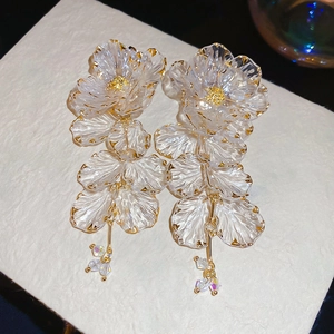 Detailed macro view of acrylic flower earrings with gold edges and crystal drops