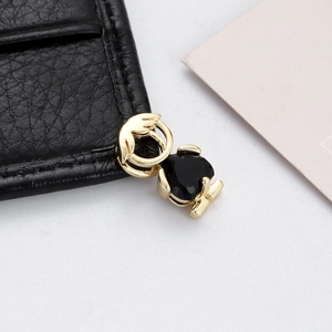 Macro detail of a golden character pendant with an inlaid black heart-shaped gemstone