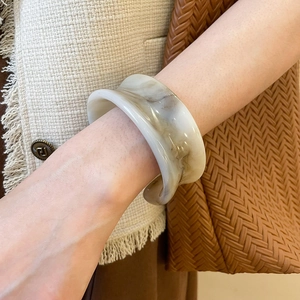 Macro detail of minimalist resin bangle with cream marble texture on a stylish wrist