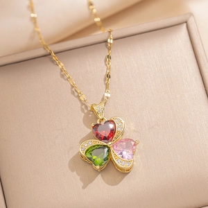 Detail of gold necklace with clover pendant made of red, green and pink heart stones