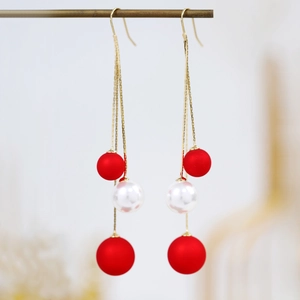 Macro shot of elegant long tassel earrings with red frosted beads and white pearls