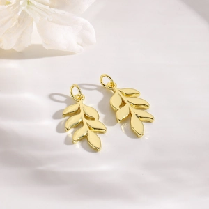 Elegant gold leaf-shaped copper pendants on a clean white surface for DIY jewelry making