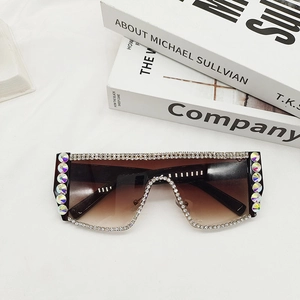 Détail rapproché de lunettes de soleil oversize avec strass et verres dégradés marron sur tissu