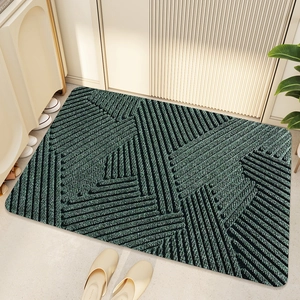 Close-up of deep green PVC coil doormat with geometric stripes in a home entryway