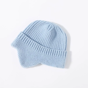 Close-up of light blue knitted earflap hat showing detailed warm cable knit texture