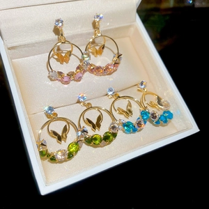 Macro shot of gold butterfly earrings with colorful zircon stones in a velvet jewelry box