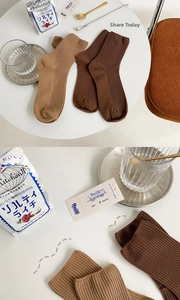 Detail of ribbed knit cotton socks in warm khaki and coffee tones on a white table