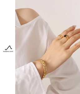 Detail of gold watchband link bracelet and smiley face ring on a model wrist
