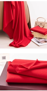 Detailed shot of luxurious red wool scarf texture with fine tassels and twill weave
