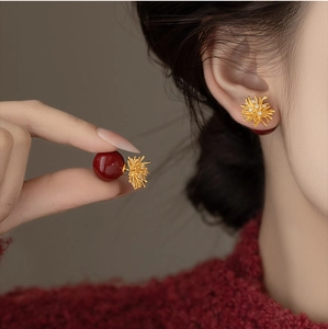 Detail of sunburst gold stud earrings with deep red beads and sparkling white crystals