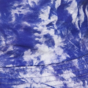 Détail macro du bord du chapeau bob tie-dye avec coutures renforcées et motifs nuages