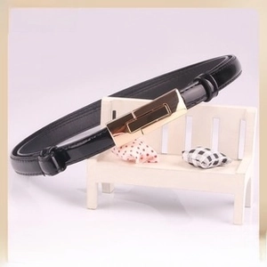 Detail of black faux leather belt featuring a sleek gold rectangular metal pin buckle