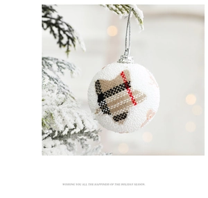 Close-up of white foam Christmas ball with plaid star fabric on a snowy tree branch