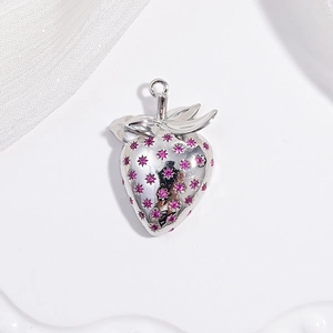 Detailed macro shot of a silver strawberry pendant featuring sparkling pink gemstones