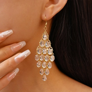 Close-up of elegant gold tassel earrings with clear crystal beads on model's ear